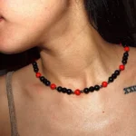 Collar de cuentas de ágata roja y hematita oscura, destacando sobre el cuello de una persona. La energía vibrante del ágata se combina con la fuerza protectora del hematita para crear una joya única.
