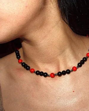 Collar de cuentas de ágata roja y hematita oscura, destacando sobre el cuello de una persona. La energía vibrante del ágata se combina con la fuerza protectora del hematita para crear una joya única.