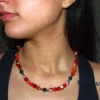 Collar de cuentas de ágata roja y hematita oscura, destacando sobre el cuello de una persona. La energía vibrante del ágata se combina con la fuerza protectora del hematita para crear una joya única.
