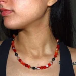 Collar de cuentas de ágata roja y hematita oscura, destacando sobre el cuello de una persona. La energía vibrante del ágata se combina con la fuerza protectora del hematita para crear una joya única.