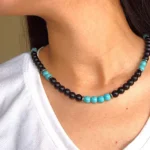 Close-up of a model wearing a handcrafted turquoise and black onyx necklace, paired with a white textured top for a casual boho look.