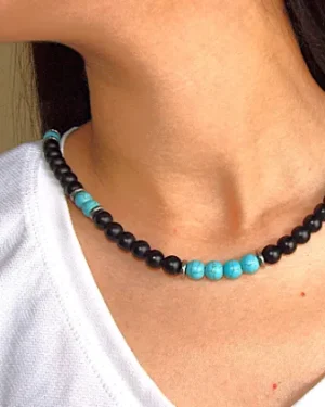 Close-up of a model wearing a handcrafted turquoise and black onyx necklace, paired with a white textured top for a casual boho look.