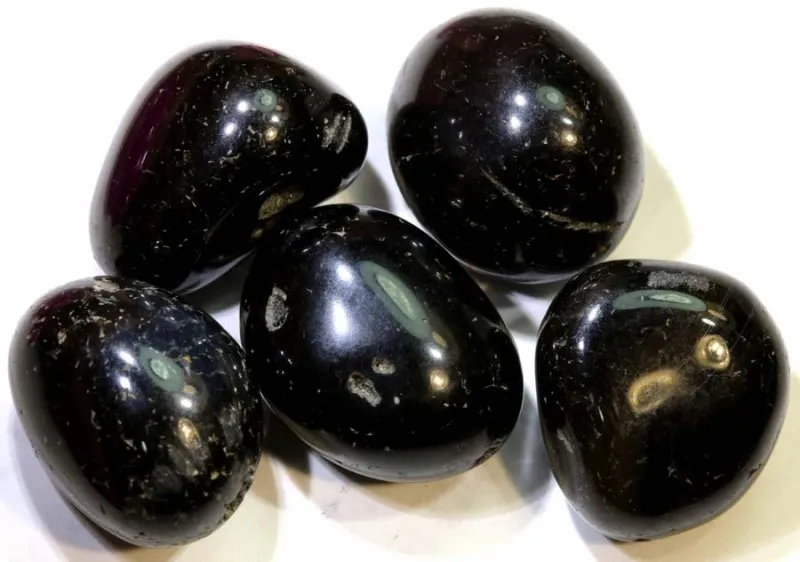 Five tumbled black agate energy stones with natural surface patterns and a polished glossy finish.