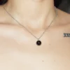 A close-up lifestyle image of a woman wearing a round Black Agate crystal necklace; highly regarded as healing crystals for grounding and protection.