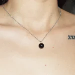 A close-up lifestyle image of a woman wearing a round Black Agate crystal necklace; highly regarded as healing crystals for grounding and protection.