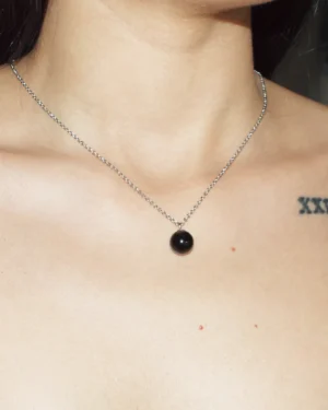A close-up lifestyle image of a woman wearing a round Black Agate crystal necklace; highly regarded as healing crystals for grounding and protection.