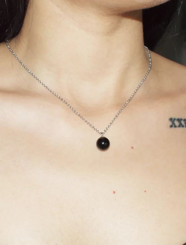 A close-up lifestyle image of a woman wearing a round Black Agate crystal necklace; highly regarded as healing crystals for grounding and protection.