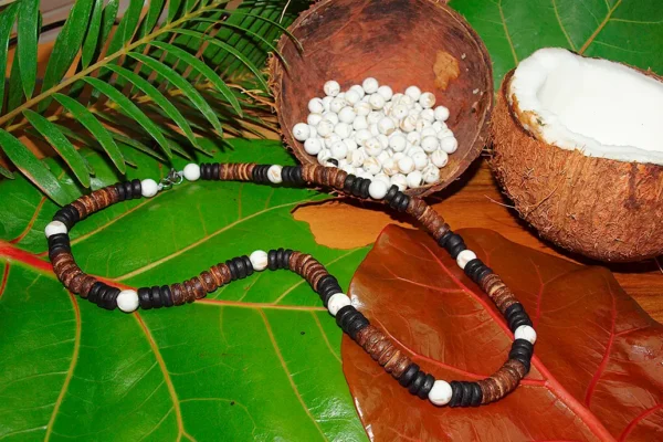 Handmade necklace featuring authentic Queen Conch shell beads and rustic coconut wood spacers, displayed on lush tropical leaves with raw materials.