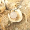 Rose Quartz sphere pendant necklace on sand and shells for love and heart chakra healing.