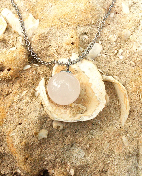 Rose Quartz sphere pendant necklace on sand and shells for love and heart chakra healing.