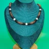 Handcrafted Queen Conch and coconut shell beaded necklace showcased on a teal jewelry mannequin bust with a wood base.