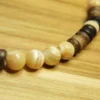Macro close-up of four polished round Trochus shell beads with natural cream and white swirls on a wooden surface.