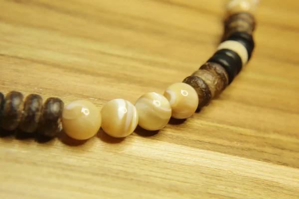 Macro close-up of four polished round Trochus shell beads with natural cream and white swirls on a wooden surface.