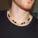 Close-up of a man wearing a handmade Trochus Shell and Coconut Beaded Necklace, showcasing the natural beach style jewelry for men's protection and well-being.